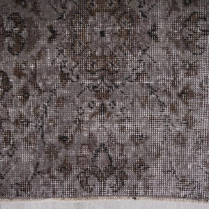 May include: A vintage rug with a faded brown and white geometric pattern. The rug has a distressed look and is made of a woven material.