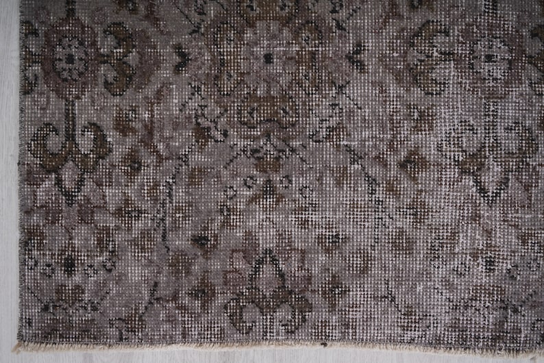 May include: A vintage rug with a faded brown and white geometric pattern. The rug has a distressed look and is made of a woven material.