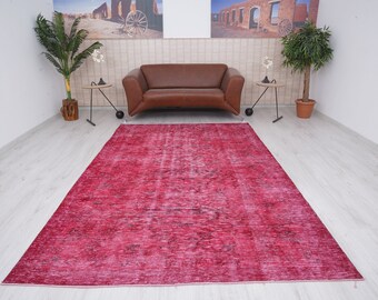 Könnte beinhalten: Ein großer, rechteckiger Teppich in einem leuchtenden Rotton mit einem Design im Used-Look im Vintage-Stil. Das Muster des Teppichs weist subtile Farbvariationen auf, die ein strukturiertes Aussehen erzeugen. Geeignet für Wohn- und Schlafzimmer.