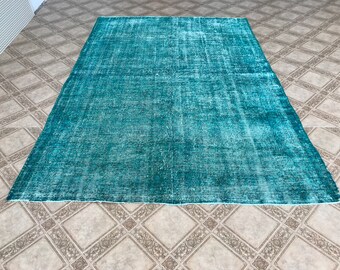 May include: A teal blue vintage rug with a distressed look. The rug has a faded, worn appearance, giving it a unique and rustic charm.