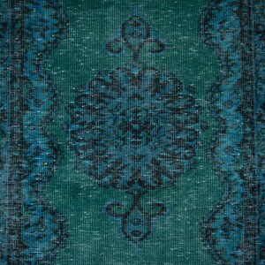 May include: A vintage teal and blue rug with a floral pattern. The rug has a distressed look and is made of a soft, woven material.