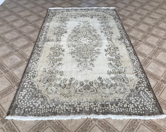 May include: A vintage rug with a white background and a brown floral pattern. The rug has a fringe border.
