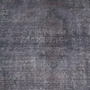 May include: A close-up of a distressed, dark gray rug with a textured surface. The rug has a vertical striped pattern with lighter gray and white accents, creating a vintage or antique appearance.