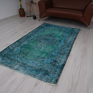 May include: A teal and blue vintage rug with a faded floral pattern. The rug has a distressed look and is perfect for adding a touch of bohemian style to any room.
