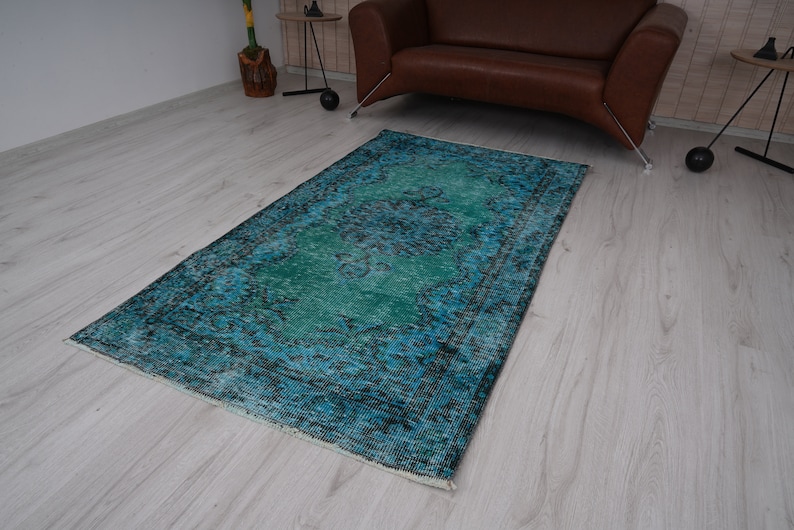 May include: A teal and blue vintage rug with a faded floral pattern. The rug has a distressed look and is perfect for adding a touch of bohemian style to any room.