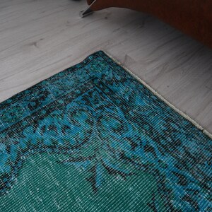 May include: A teal and blue patterned rug with a white fringe border. The rug has a vintage, distressed look.