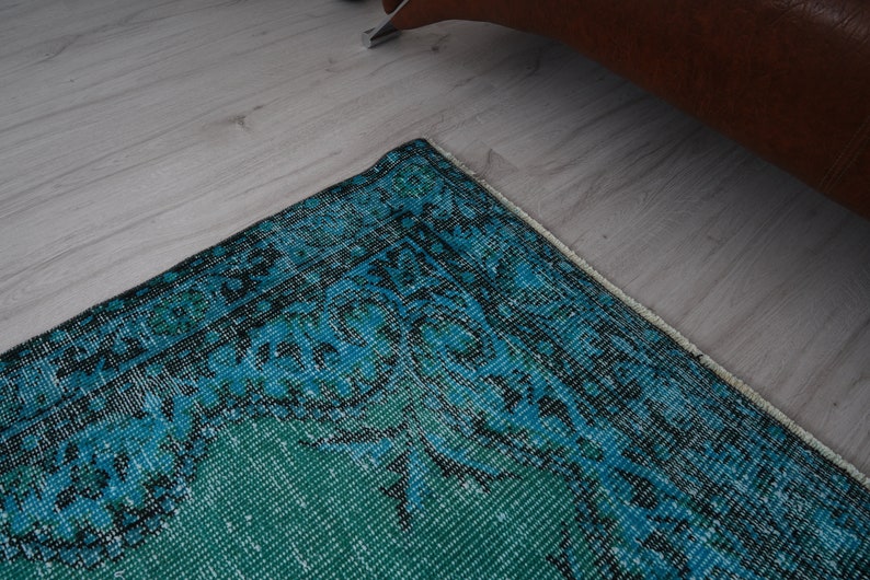 May include: A teal and blue patterned rug with a white fringe border. The rug has a vintage, distressed look.