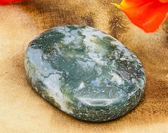 Könnte beinhalten: Ein grüner, weißer und grauer Achat-Stein mit einer glatten, polierten Oberfläche. Der Stein ist oval geformt und hat ein natürliches, organisches Muster.