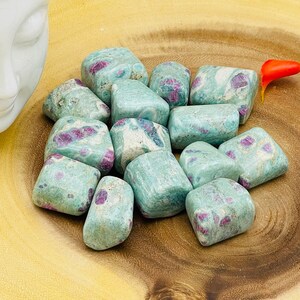 May include: A collection of tumbled green and pink ruby in zoisite stones. The stones are smooth and polished, with a variety of shapes and sizes.