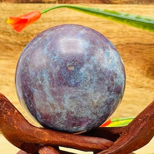 May include: A blue and purple gemstone sphere on a wooden stand. The sphere has a swirling pattern of blue and purple.