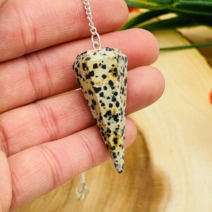 May include: A white and black dalmatian jasper pendulum with a silver chain.