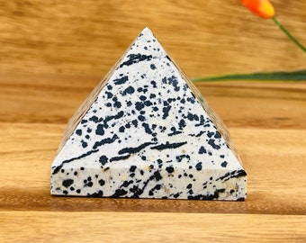 Könnte beinhalten: Eine schwarze und weiße Dalmatiner-Jaspis-Pyramide aus Kristall. Die Pyramide besteht aus poliertem Stein und hat eine glatte, glänzende Oberfläche.