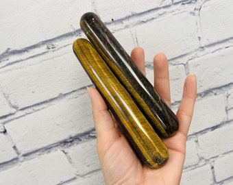 Puede incluir: Dos varitas de cristal de ojo de tigre, una de color marrón dorado y la otra de color negro y dorado.
