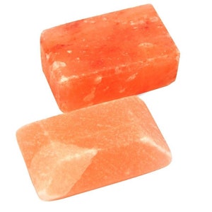 May include: Two rectangular blocks of Himalayan pink salt. The blocks are different sizes and have a rough, textured surface.