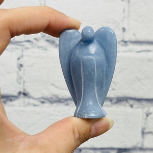 May include: A small, light blue angel figurine carved from a single piece of stone. The angel has wings and a simple, elegant design.