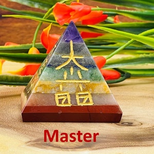 Pu&ograve; includere: Una piramide a sette strati realizzata con pietre di diversi colori, con caratteri cinesi dorati sul davanti. La piramide &egrave; appoggiata su una superficie di legno. Maestro.