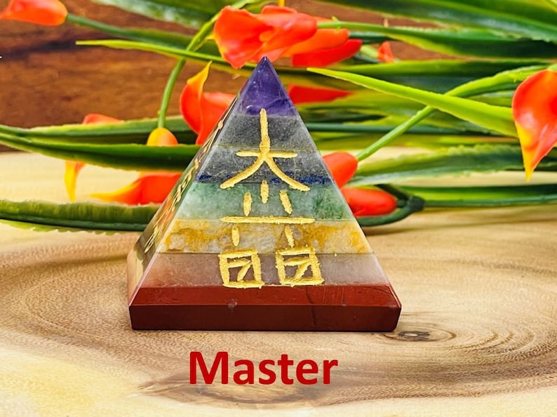 Pu&ograve; includere: Una piramide a sette strati realizzata con pietre di diversi colori, con caratteri cinesi dorati sul davanti. La piramide &egrave; appoggiata su una superficie di legno. Maestro.
