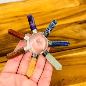 K&ouml;nnte beinhalten: Ein siebenspitziges Chakra-Balancing-Set aus Kristallen mit einem klaren Quarzkristall in der Mitte. Die Spitzen bestehen aus Amethyst, Karneol, klarem Quarz, Citrin, Aventurin, Rosenquarz und Sodalith.