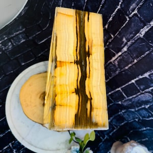 May include: A rectangular, yellow and brown onyx lamp base with a wood base. The lamp base has a natural, striated pattern.