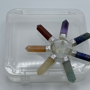 K&ouml;nnte beinhalten: Ein siebenspitziges Chakra-Set aus Kristallen mit einem klaren Quarzzentrum, bestehend aus Amethyst, Lapislazuli, gr&uuml;nem Aventurin, Citrin, Karneol und rotem Jaspis.