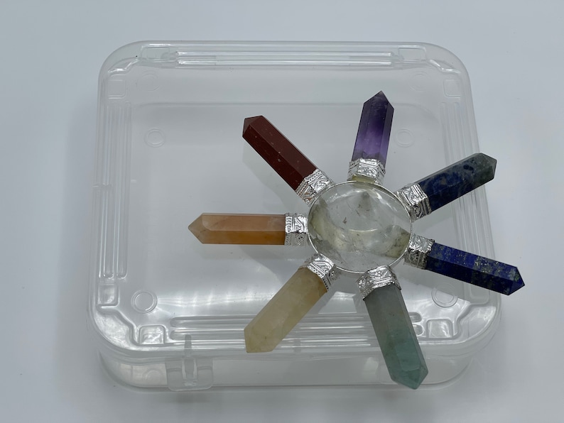 K&ouml;nnte beinhalten: Ein siebenspitziges Chakra-Set aus Kristallen mit einem klaren Quarzzentrum, bestehend aus Amethyst, Lapislazuli, gr&uuml;nem Aventurin, Citrin, Karneol und rotem Jaspis.