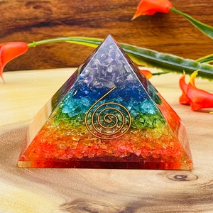 May include: A rainbow crystal pyramid with a gold wire spiral inside. The pyramid is made of seven layers of different colored crystals, representing the seven chakras.