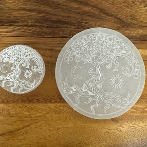 May include: Two white selenite charging plates with a tree of life design. The larger plate is 8 inches in diameter and the smaller plate is 4 inches in diameter.