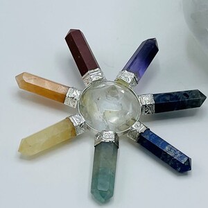K&ouml;nnte beinhalten: Ein siebenspitziges Chakra-Set aus Kristallen mit klarem Quarz in der Mitte und Spitzen aus roten, orangefarbenen, gelben, gr&uuml;nen, blauen, indigofarbenen und violetten Kristallen.