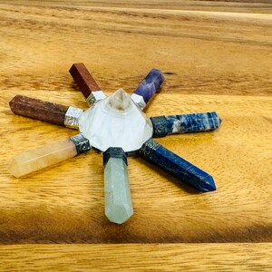 K&ouml;nnte beinhalten: Ein siebenspitziges Chakra-Set aus Kristallen mit einer klaren Quarzpyramide in der Mitte. Das Set enth&auml;lt sieben Kristallspitzen in den Farben der Chakren: Rot, Orange, Gelb, Gr&uuml;n, Blau, Indigo und Violett.