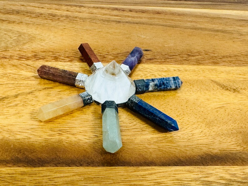 K&ouml;nnte beinhalten: Ein siebenspitziges Chakra-Set aus Kristallen mit einer klaren Quarzpyramide in der Mitte. Das Set enth&auml;lt sieben Kristallspitzen in den Farben der Chakren: Rot, Orange, Gelb, Gr&uuml;n, Blau, Indigo und Violett.