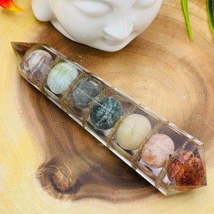 May include: A clear crystal point with a gold-toned base, containing a variety of colorful stones, including green, brown, white, and pink.