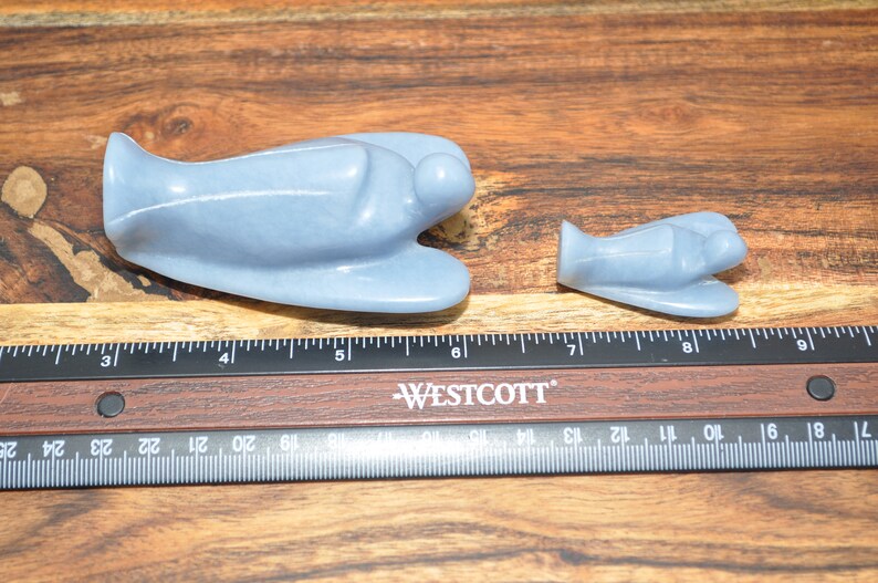 May include: Two blue angel figurines carved from stone. The larger angel is about 5 inches long and the smaller angel is about 3 inches long.