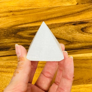 May include: A white selenite pyramid crystal, a type of mineral known for its calming and purifying properties.