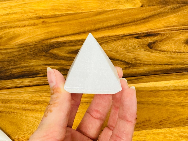 May include: A white selenite pyramid crystal, a type of mineral known for its calming and purifying properties.