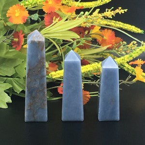 May include: Three blue agate crystal points of varying sizes. The points are smooth and polished, with a light blue color and a hint of white. The points are arranged in a row, with the largest point on the left and the smallest point on the right.