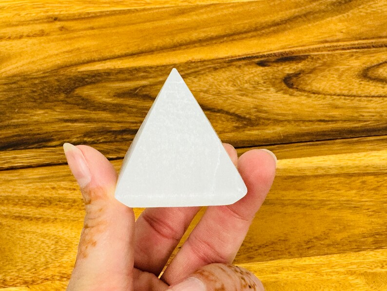 May include: A white selenite pyramid crystal, a type of mineral known for its calming and purifying properties.