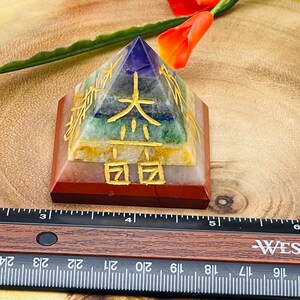 Pu&ograve; includere: Una piramide a sette chakra realizzata con diverse pietre, tra cui ametista, sodalite, aventurina verde, citrino, corniola, diaspro rosso e quarzo trasparente. La piramide &egrave; incisa con caratteri cinesi dorati.