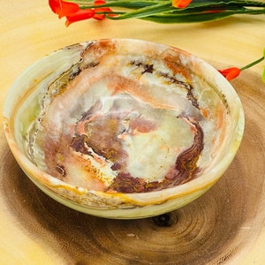 May include: A green, brown, and white onyx bowl with swirling patterns. The bowl is round and has a smooth, polished finish.