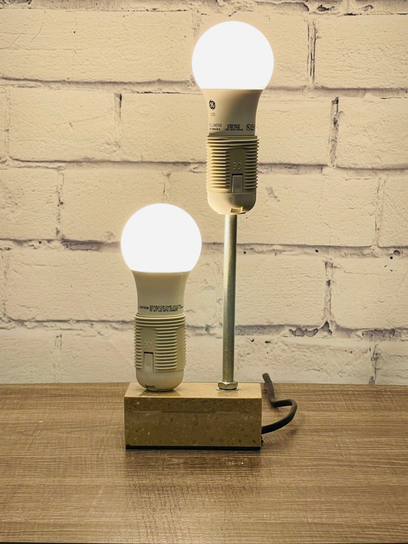 May include: A DIY lamp made from two LED light bulbs and a metal rod. The lamp is mounted on a rectangular stone base and has a black cord.