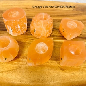 May include: Six orange selenite candle holders in various shapes, including a cylinder, heart, and oval. The holders are labeled A through F.