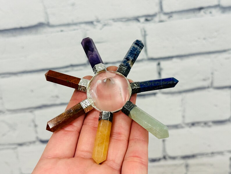 K&ouml;nnte beinhalten: Ein siebenspitziges Chakra-Set aus Kristallen mit einem klaren Quarzzentrum. Die Spitzen bestehen aus Amethyst, Lapislazuli, Sodalith, klarem Quarz, Karneol, Citrin und Aventurin.