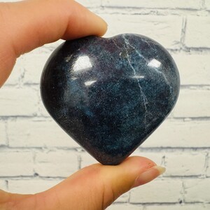 May include: A dark blue heart-shaped polished stone with white veins. The stone is smooth and has a glossy finish.