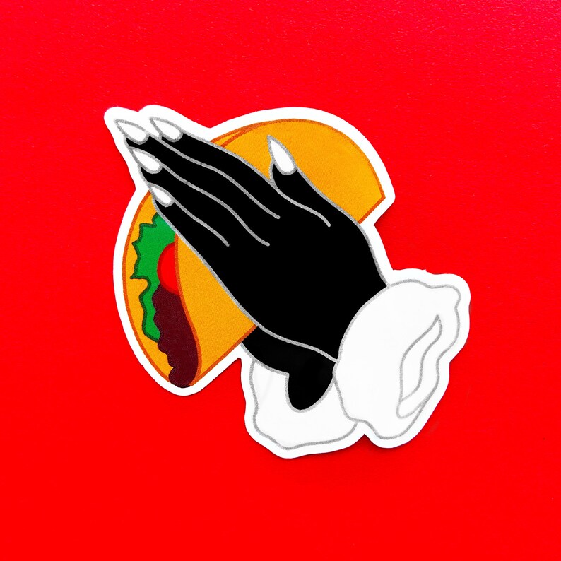 May include: A black hand with long, white fingernails is holding a yellow taco with green lettuce and red meat filling. The taco is being held up in a praying position.