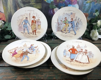Può includere: Set di quattro piatti in ceramica vintage con illustrazioni umoristiche che rappresentano scene di una fiera o di un'esposizione. Ogni piatto presenta una scena diversa con persone in vari costumi e attività. I piatti sono bianchi con un bordo color crema e hanno un'iscrizione manoscritta in francese che dice "A L'Exposition".