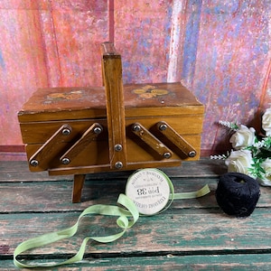Caja de costura de madera vintage con decoración floral.