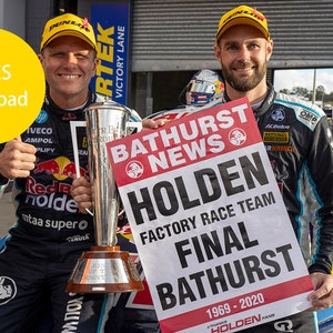 May include: Two men in racing gear holding a trophy and a sign that reads "Bathurst News Holden Factory Race Team Final Bathurst 1969-2020".