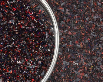 May include: Close-up of a sample of black opal chips, with a wet section on the left and a dry section on the right. The wet section has water droplets and the word "Wet". The dry section has the word "Dry".
