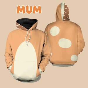 May include: A tan hoodie with a white design on the front and back. The front design is a large white oval shape. The back design is two white circles. The hoodie has a black hood lining and a white drawstring. The word "MUM" is printed in orange letters on the top of the image.