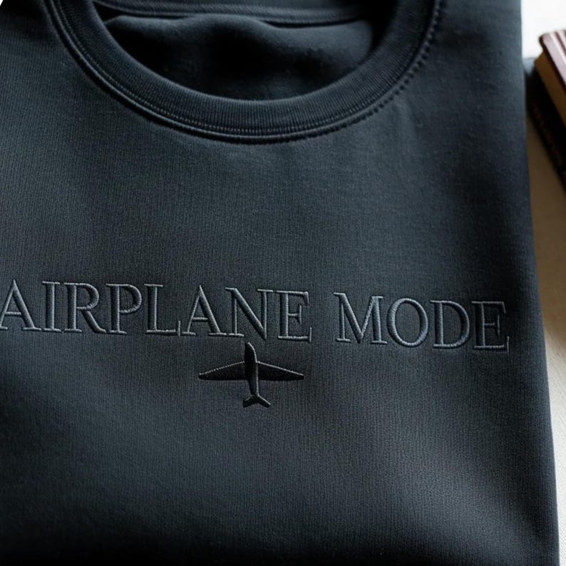 Puede incluir: Sudadera gris oscuro con el texto bordado "AIRPLANE MODE" y un peque&ntilde;o gr&aacute;fico de avi&oacute;n. La sudadera de cuello redondo est&aacute; hecha de un material suave.