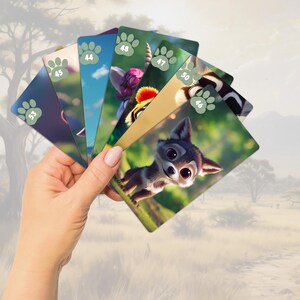 Pu&ograve; includere: Un set di carte colorate con illustrazioni di animali e numeri. Le carte sono tenute in una mano su uno sfondo sfocato di un paesaggio di savana.